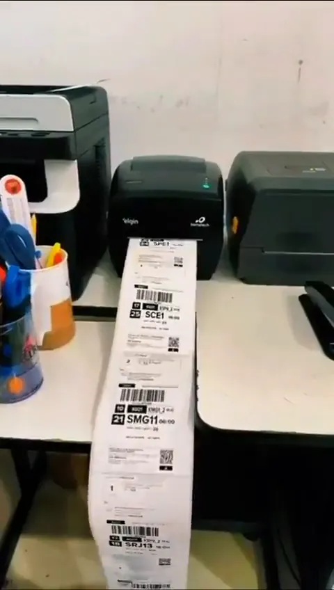 Etiquetas de envio saindo da impressora e pedidos sendo embalados